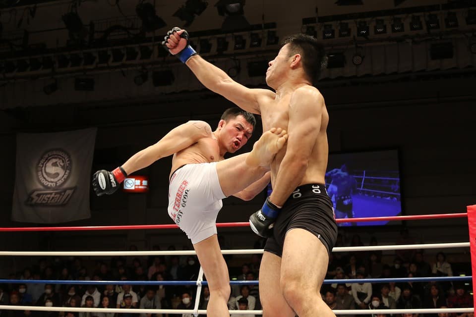 Two mixed martial artists exchanging strikes in an MMA bout in Japan