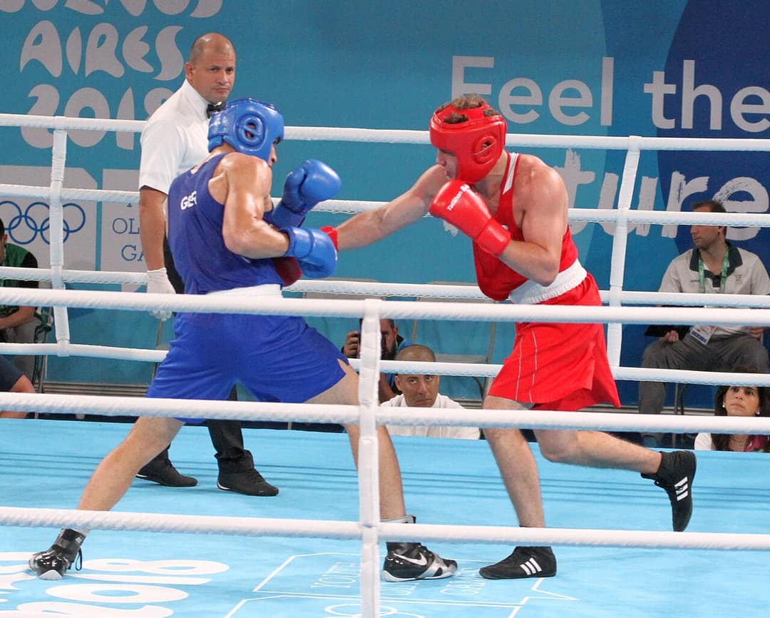 A referee looks on during an amateur boxing bout — only the referee has the authority to stop a fight
